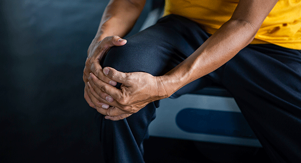 Close up person holding their knee.